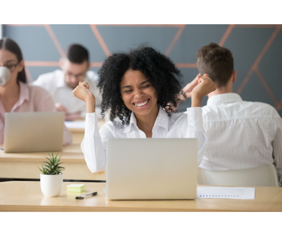 Boosting employee morale leads to happy employees. Happy employees are productive employees. Picture of a smiling woman sitting behind a computer.