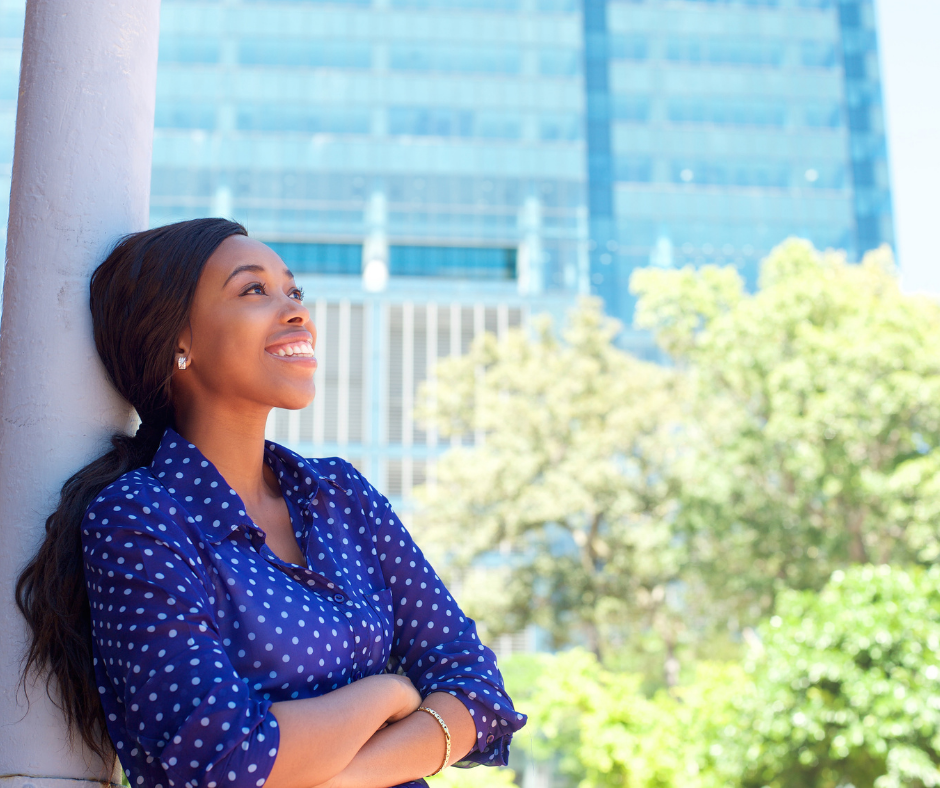 Smiling young lady who is a leader. She is leaning against a white pole.