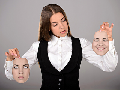 A lady holding two different masks in her hands. One mask has a serious face and the other mask is a smiling face.