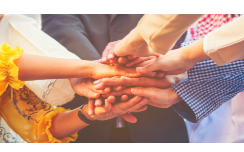 Coworkers who get along with each other. they are in a circle and have their hands staked on top of each other.