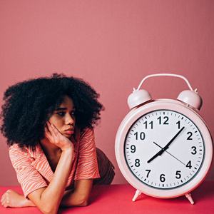 A female leader staring at a big pink clock.